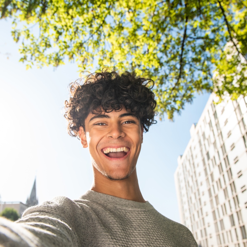 Portrait happy young man taking selfie outside in city
