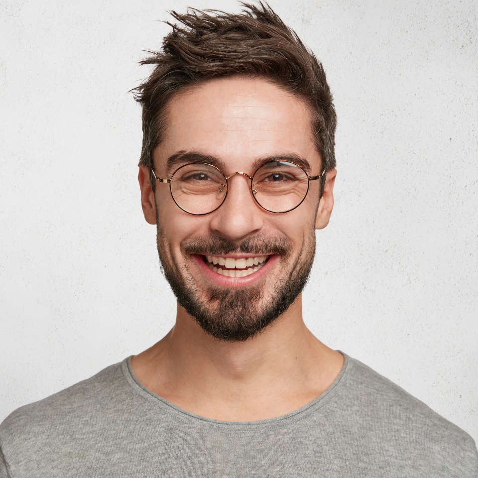 Headshot of satisfied cheerful handsome man grins at camera, glad to find suitable well paid job, isolated over white concrete background. People, positive emotions and facial expressions concept