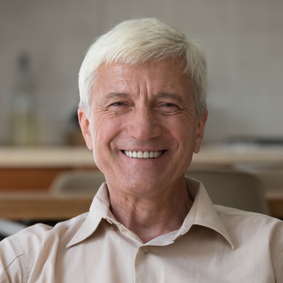 Head shot portrait handsome optimistic senior man sit indoor looking posing on camera, having wide toothy smile advertise professional dental clinic services for elders. Carefree retirement concept