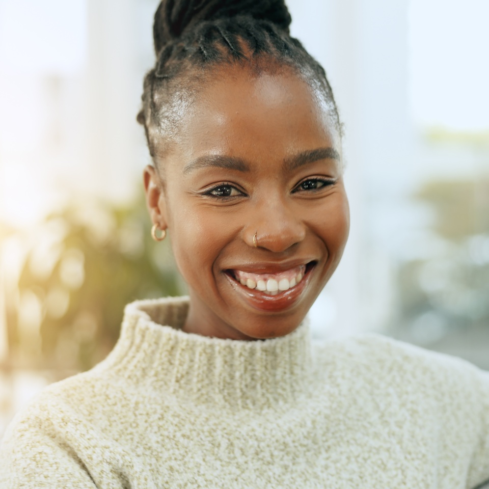 Happy, smile and portrait of black woman on a sofa for relaxing and positive attitude in living room. Excited, calm and young African female person sitting and resting in the lounge of apartment.